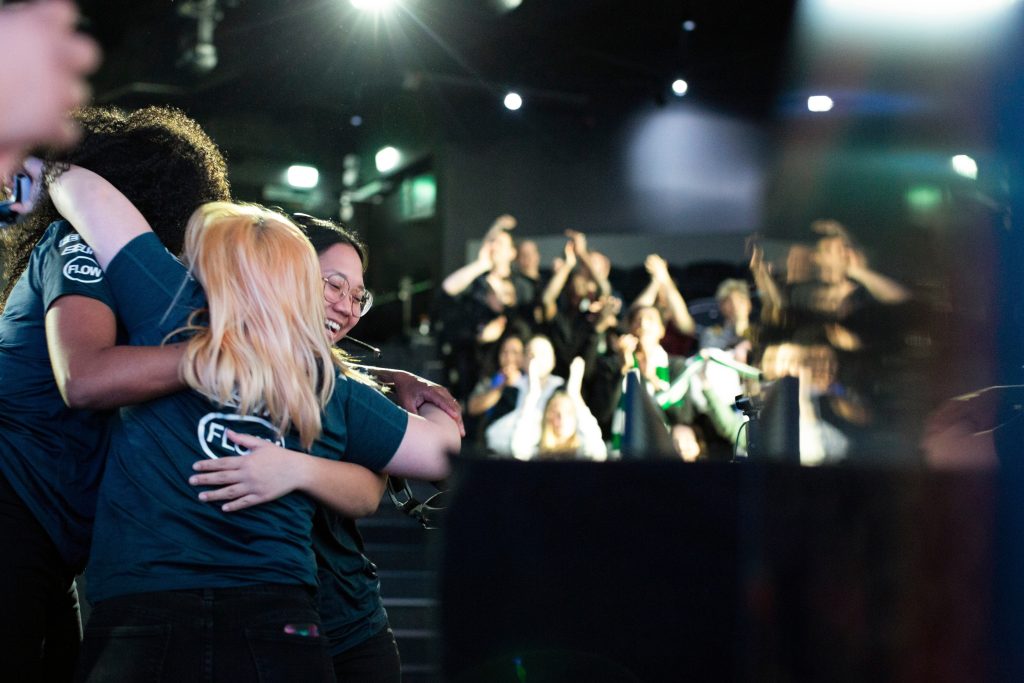 Female coach and gamers embracing while celebrating win after eSports tournament at arena