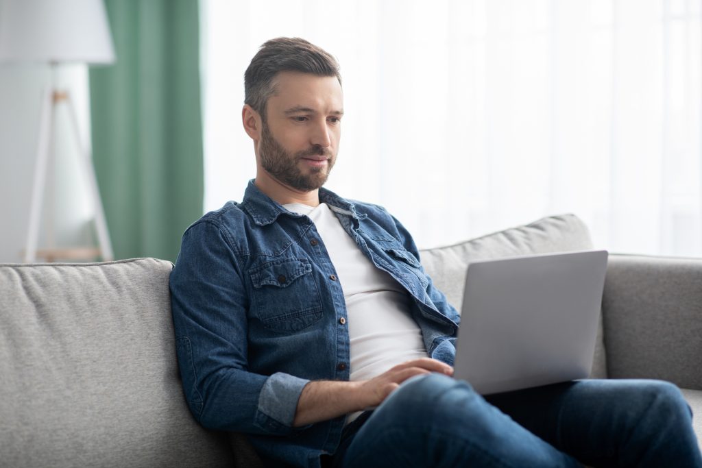 Concentrated man using computer, having part time job at home